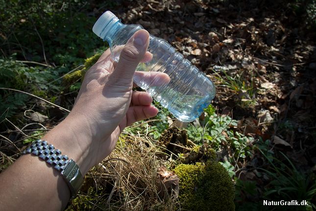 En klar vandflaske med vand, kan bruges som brændglas.